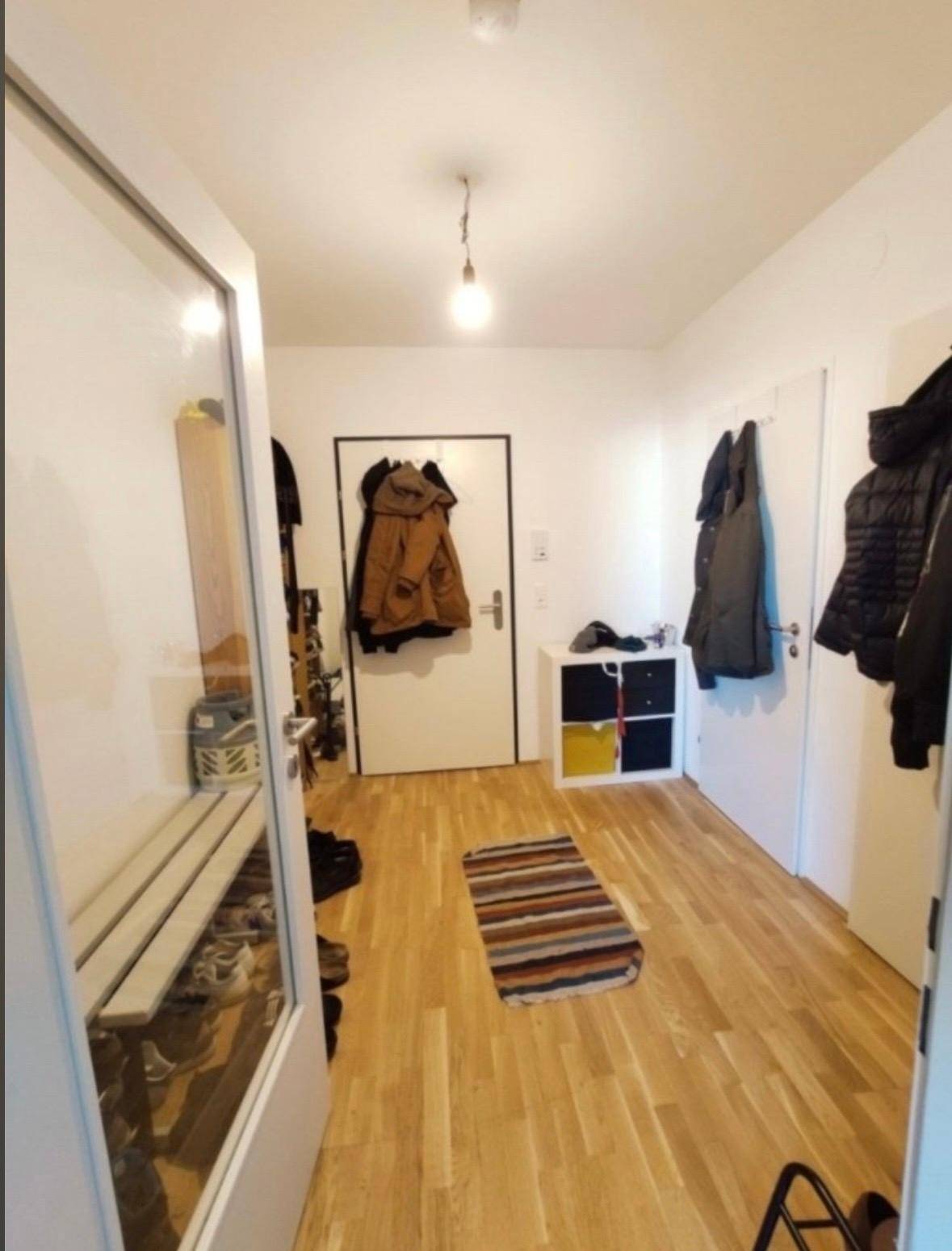 Heller Eingangsbereich mit Holzparkettboden, Garderobe und Schuhbank.