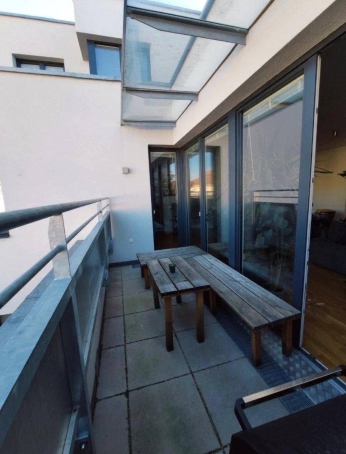 Heller Balkon mit Holzbänken und Grill, bietet einen schönen Außenbereich zum Entspannen.