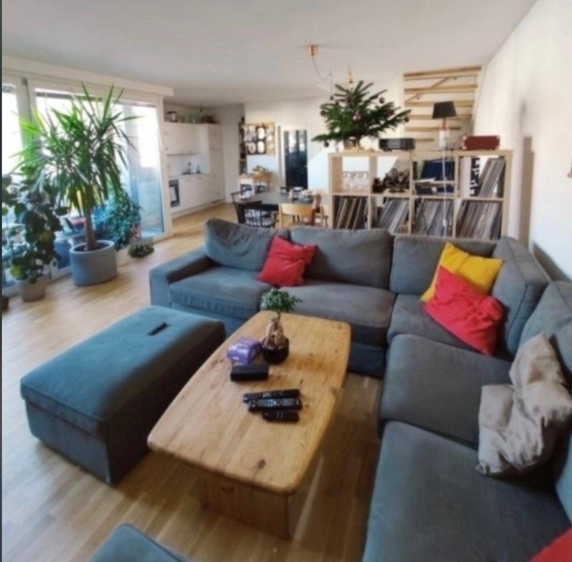 Gemütlicher Wohnbereich mit großem Ecksofa, Holztisch und Blick auf die offene Küche.