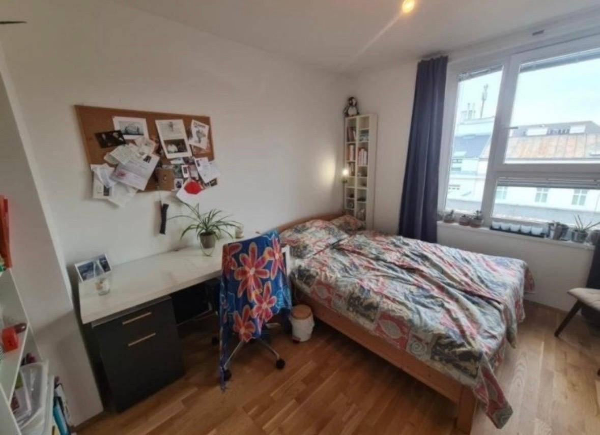 Helles Schlafzimmer mit Einzelbett, Schreibtisch und großem Fenster mit Stadtblick.