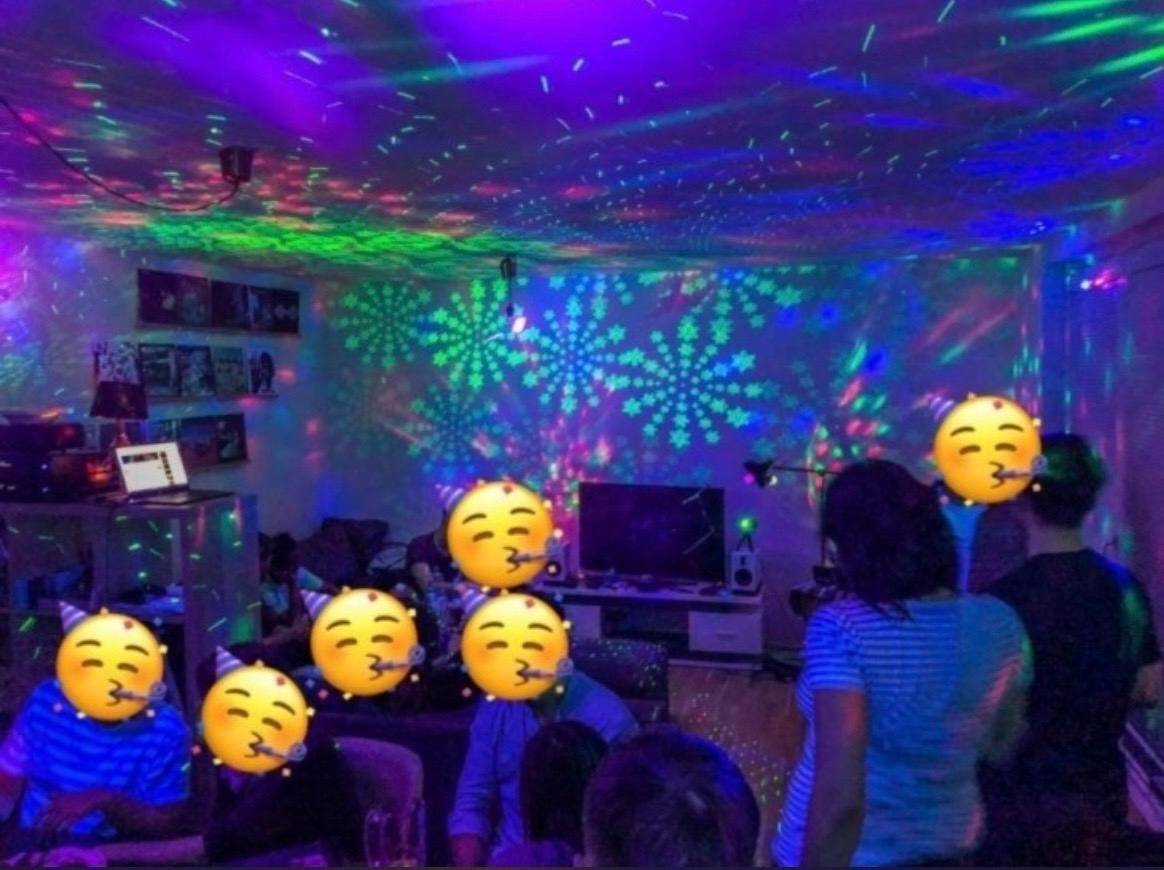 Wohnzimmer mit bunter Partybeleuchtung und mehreren Personen, die feiern.