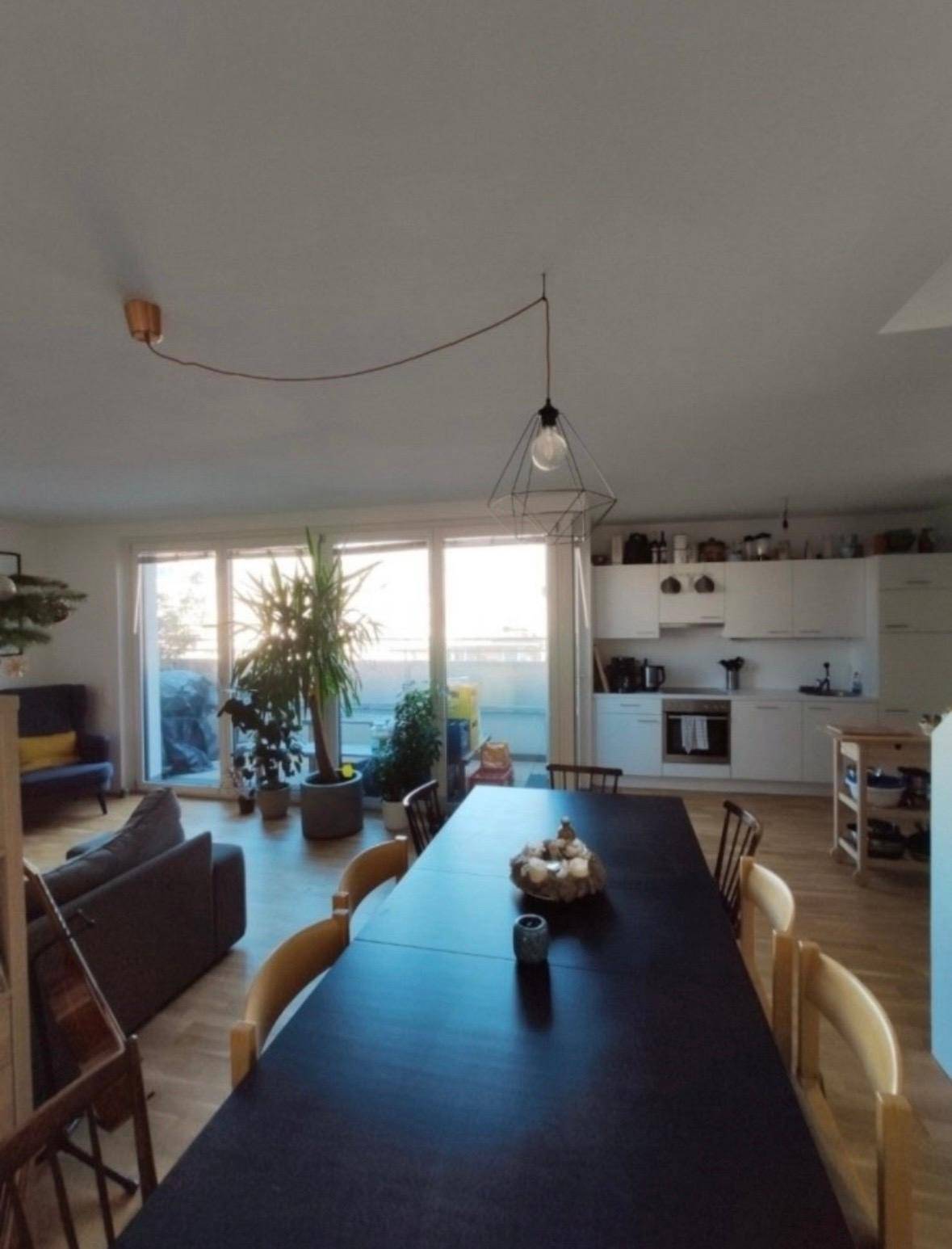 Lichtdurchfluteter Wohn-Essbereich mit Zugang zum Balkon und Blick auf die moderne Küche.