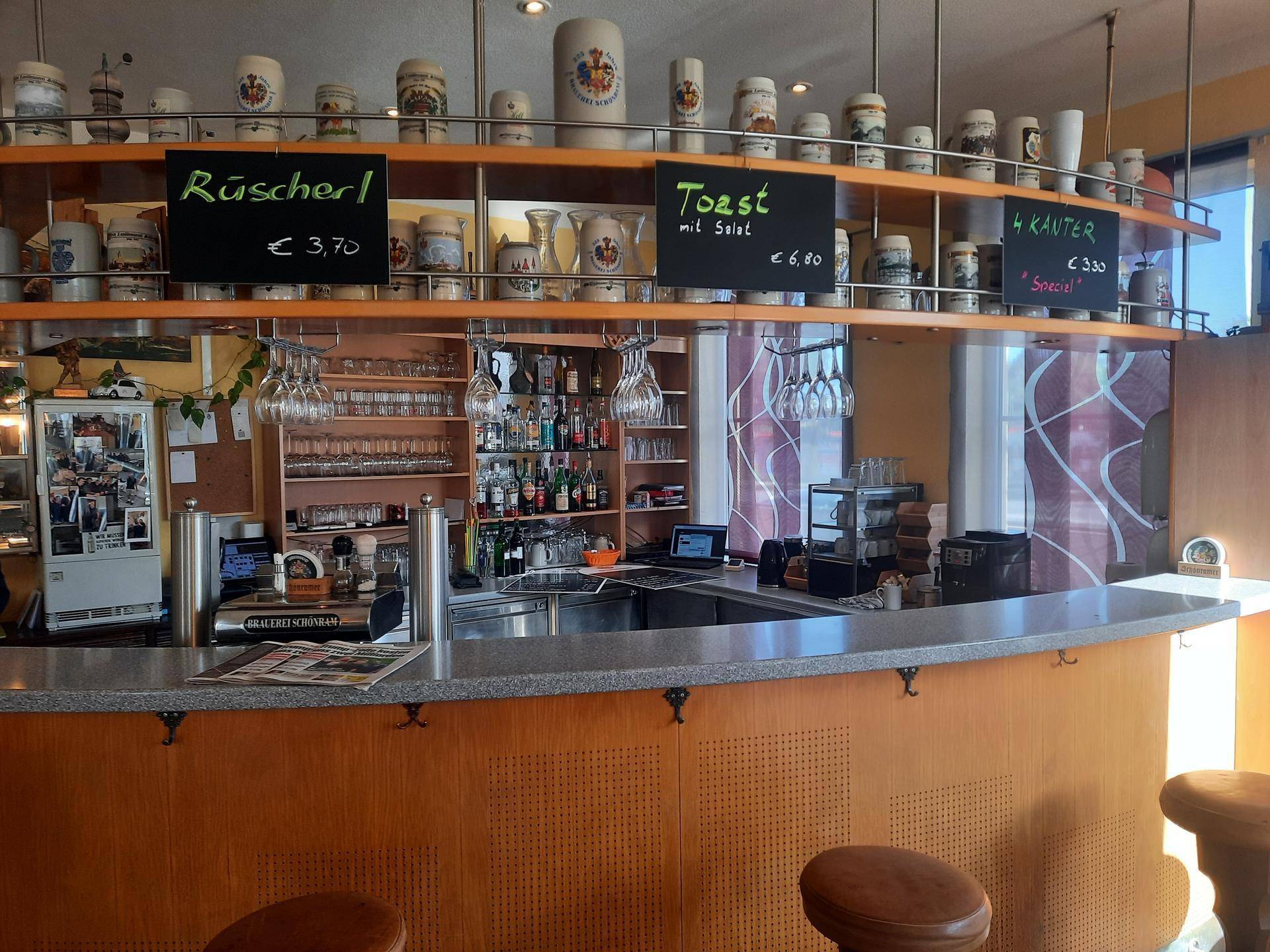 Moderne Bar mit geschwungener Theke, Barhockern und einer Auswahl an Getränken und Dekorationen.