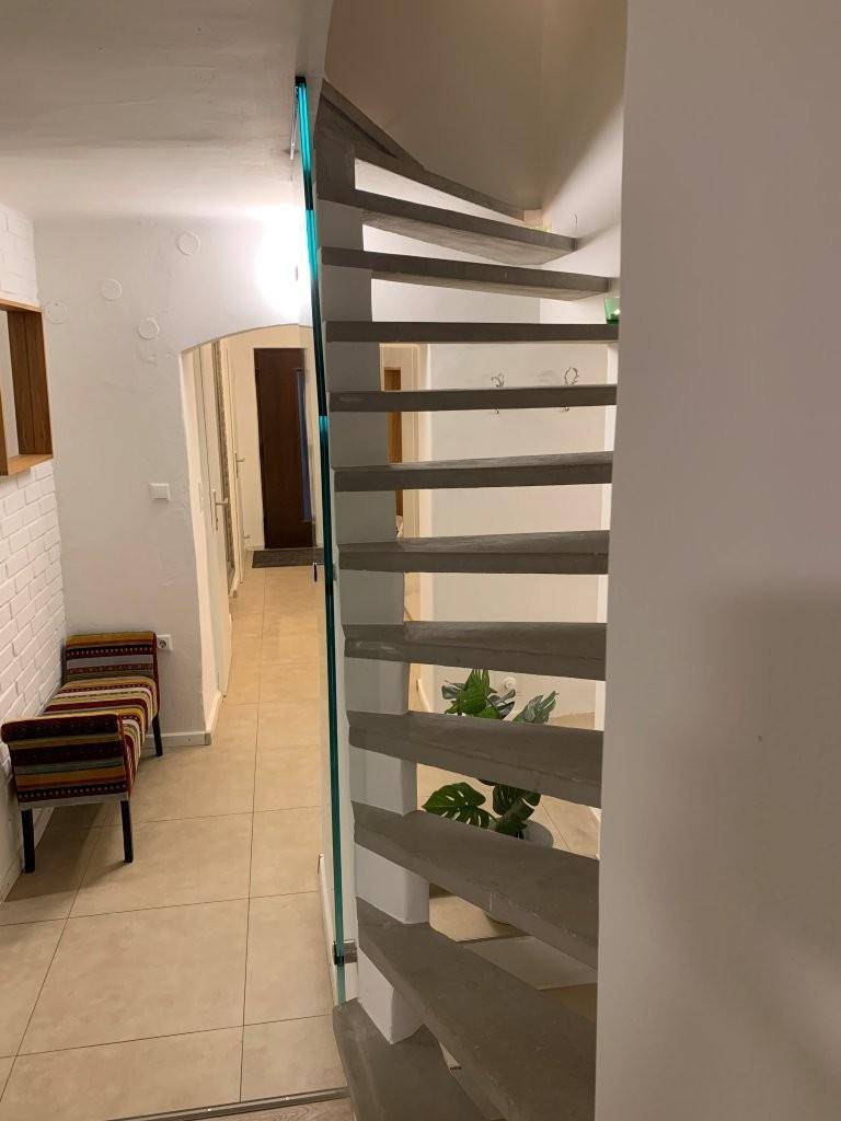 Heller Flur mit moderner Wendeltreppe und dekorativer Pflanze.