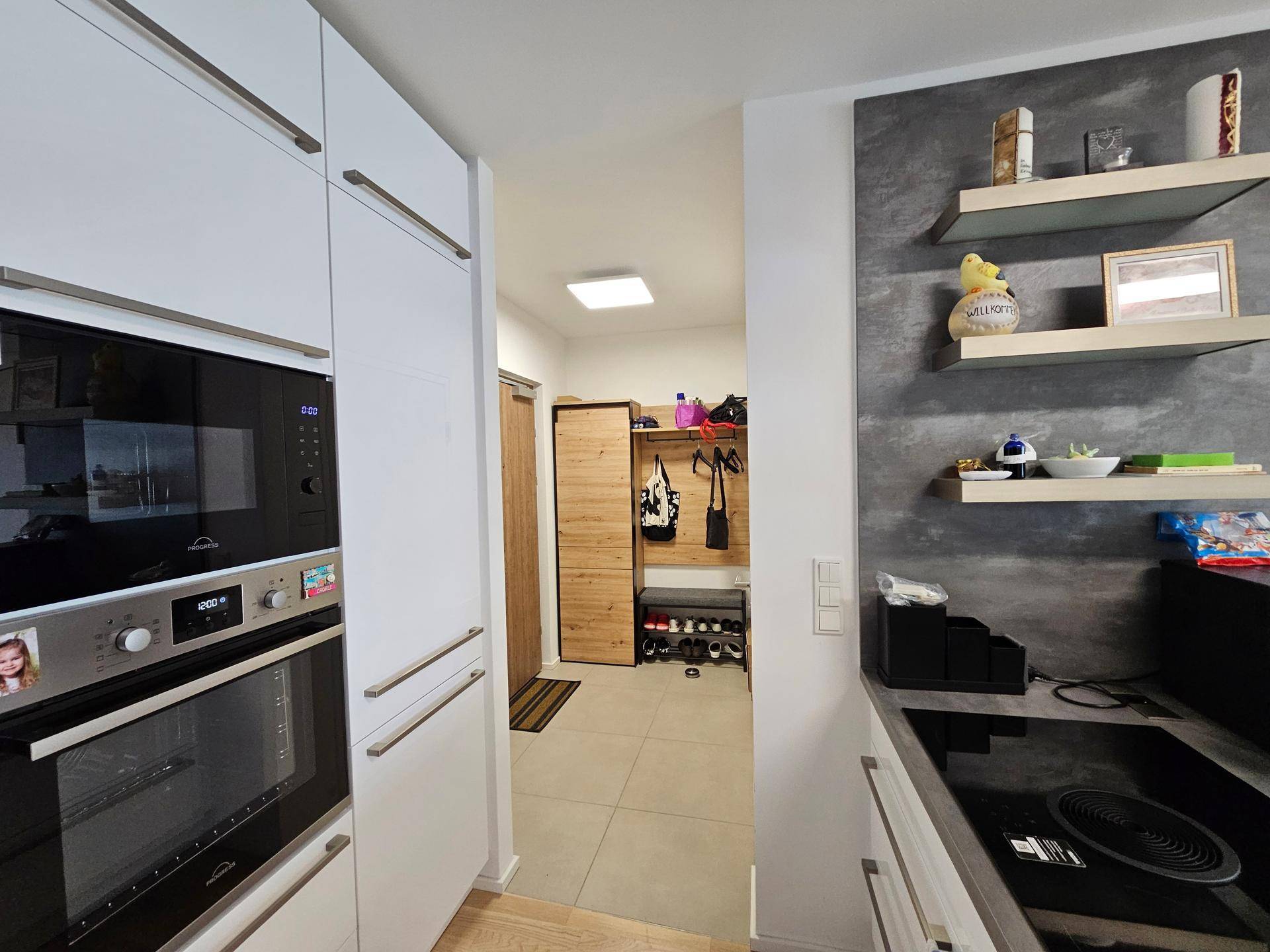 Moderner Eingangsbereich mit Garderobe und Fliesenboden, vom Küchenbereich aus gesehen.