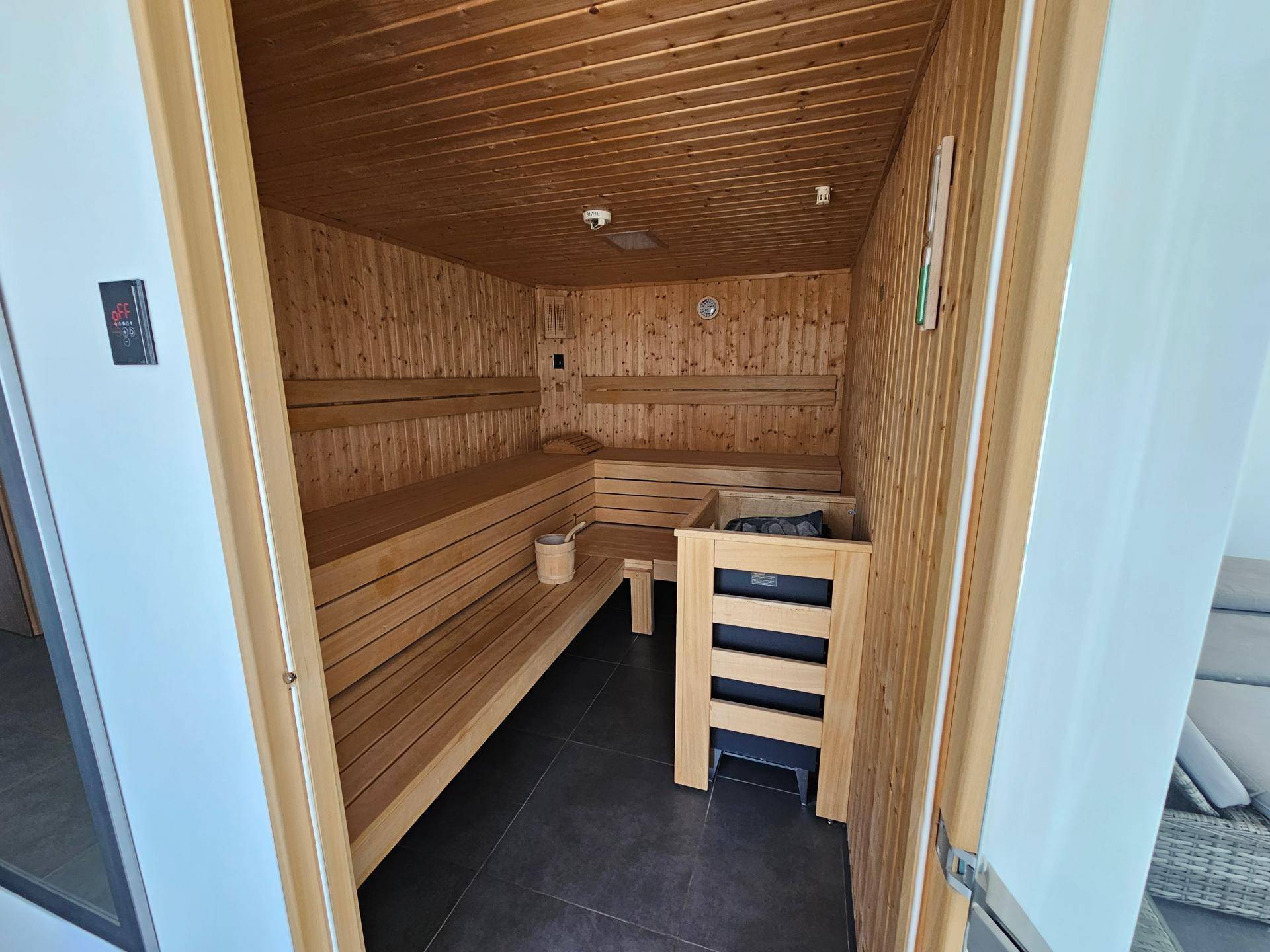 Geräumige Holzsauna mit mehreren Bänken und traditionellem Saunaofen.