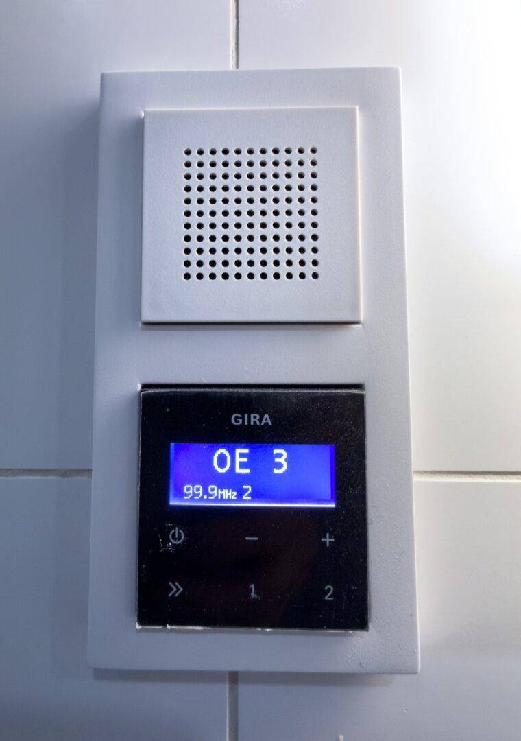Nahaufnahme eines GIRA Wandradios mit digitaler Anzeige und Bedienelementen.