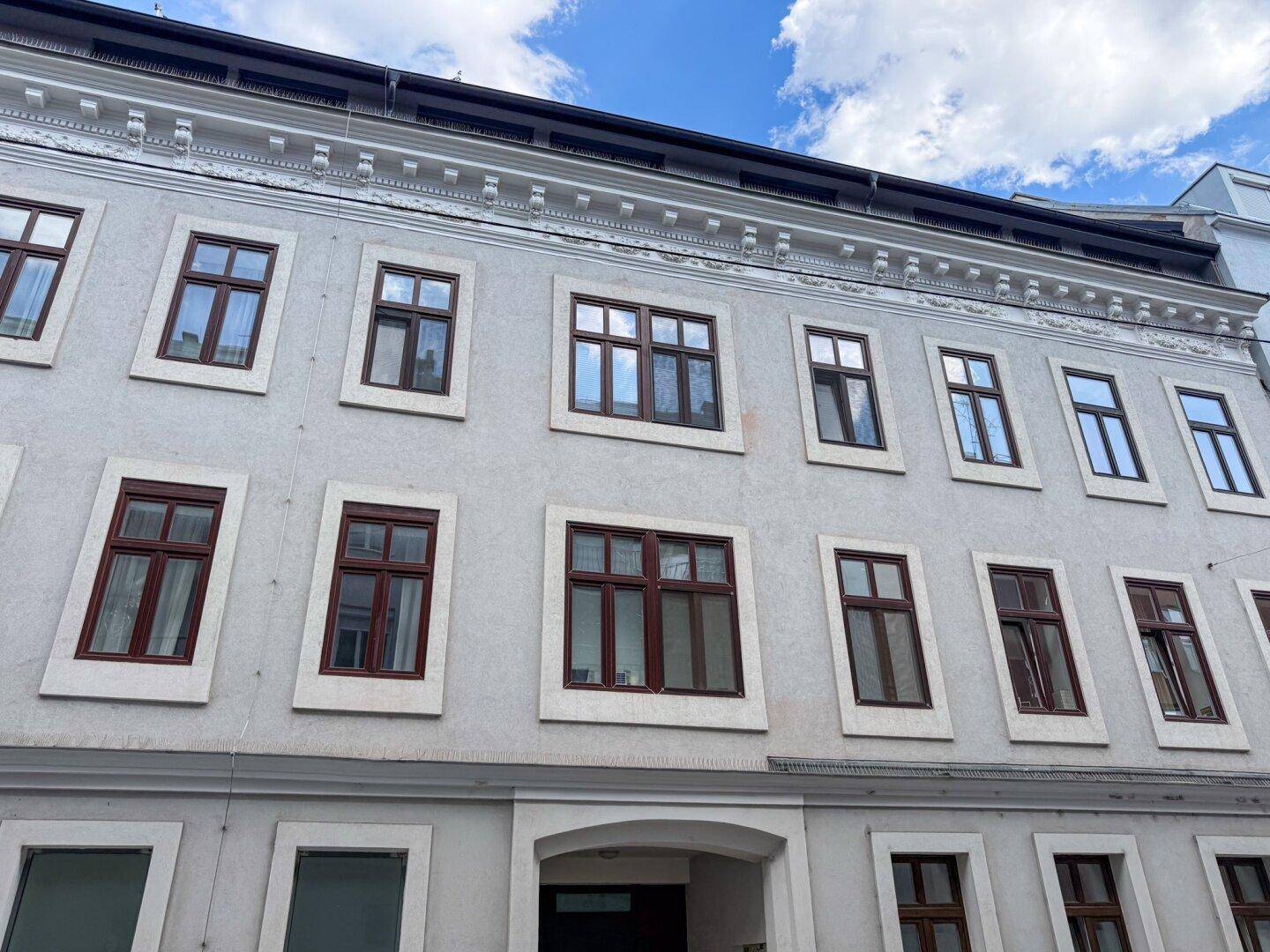 Fassade eines Mehrfamilienhauses mit zahlreichen Fenstern und klassischer Architektur.