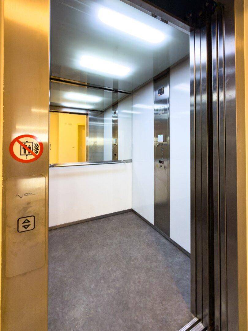 Moderner Aufzug mit Edelstahloberflächen und heller Beleuchtung im Gebäude.