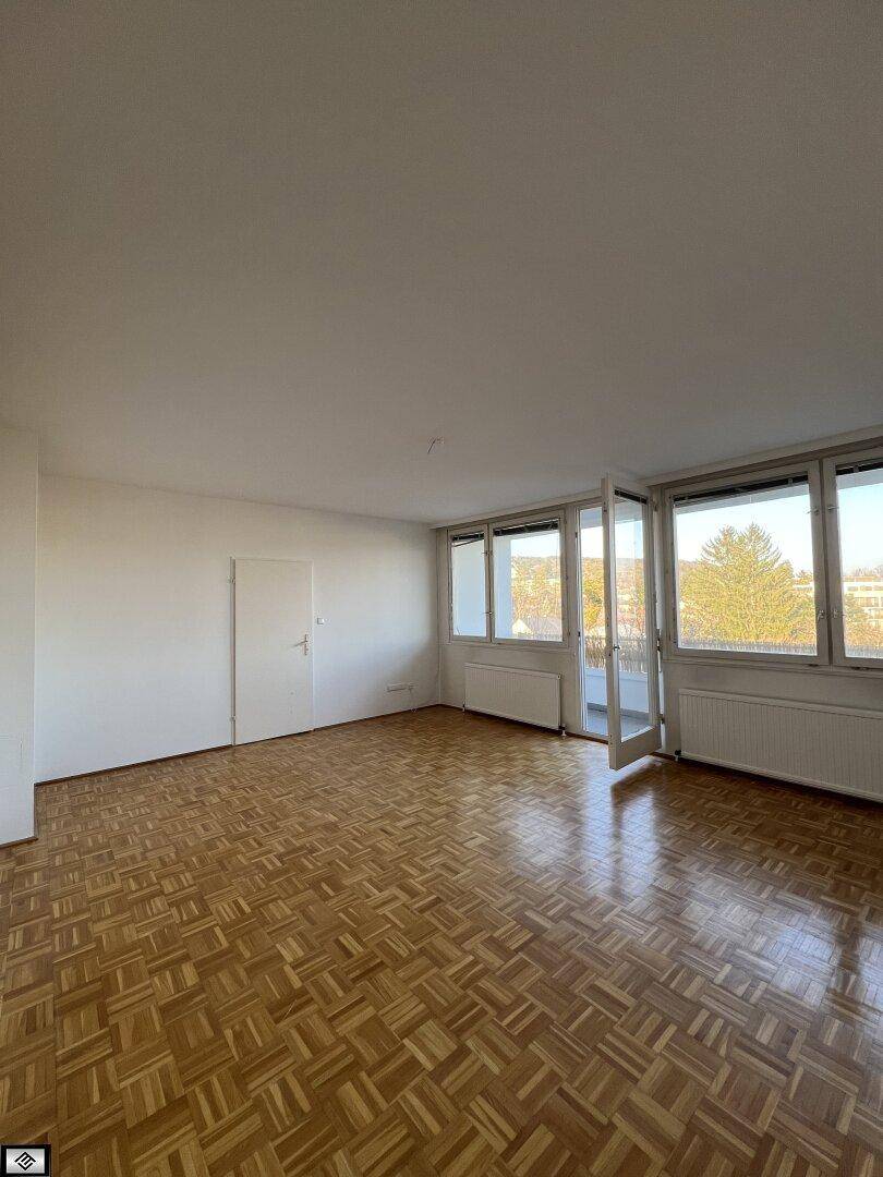 Geräumiges Zimmer mit klassischem Parkettboden und großen Fenstern für viel Tageslicht.