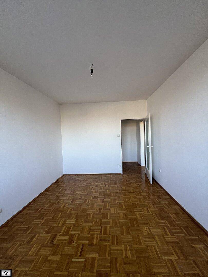 Geräumiges Schlafzimmer mit klassischem Parkettboden und weißen Wänden, bereit zur Einrichtung.