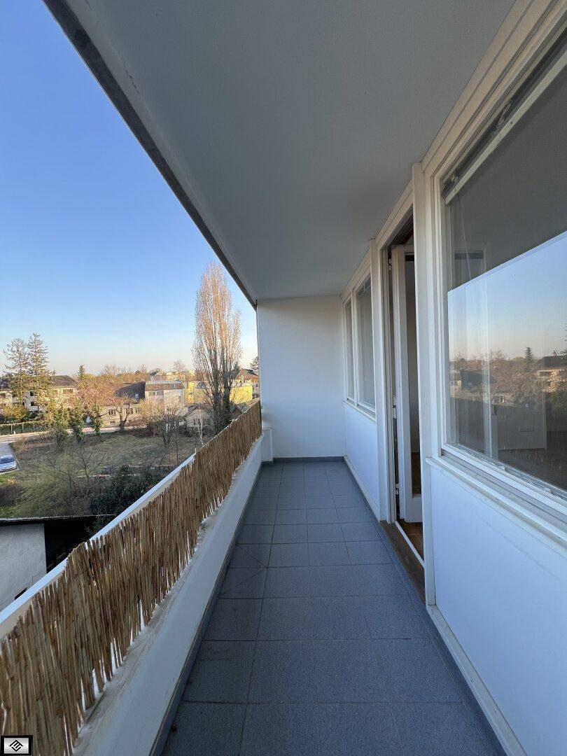 Langer Balkon mit Fliesenboden und einfacher Holzverkleidung, ideal für sonnige Stunden.