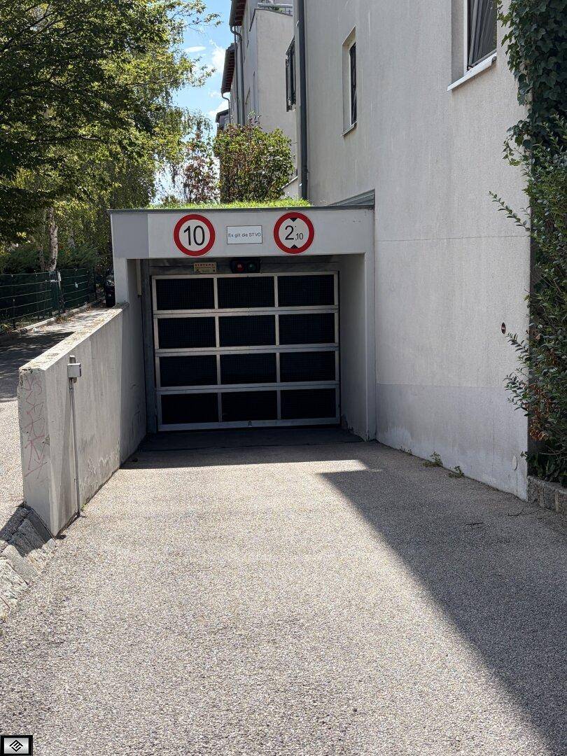 Einfahrt zu einer Tiefgarage mit Höhenbegrenzungsschildern und einer modernen Garagentür.