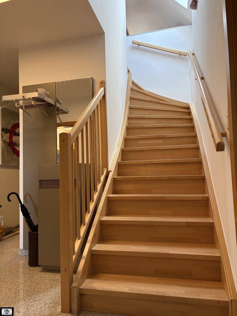 Elegante Holztreppe mit hellem Geländer, die in die obere Etage führt.