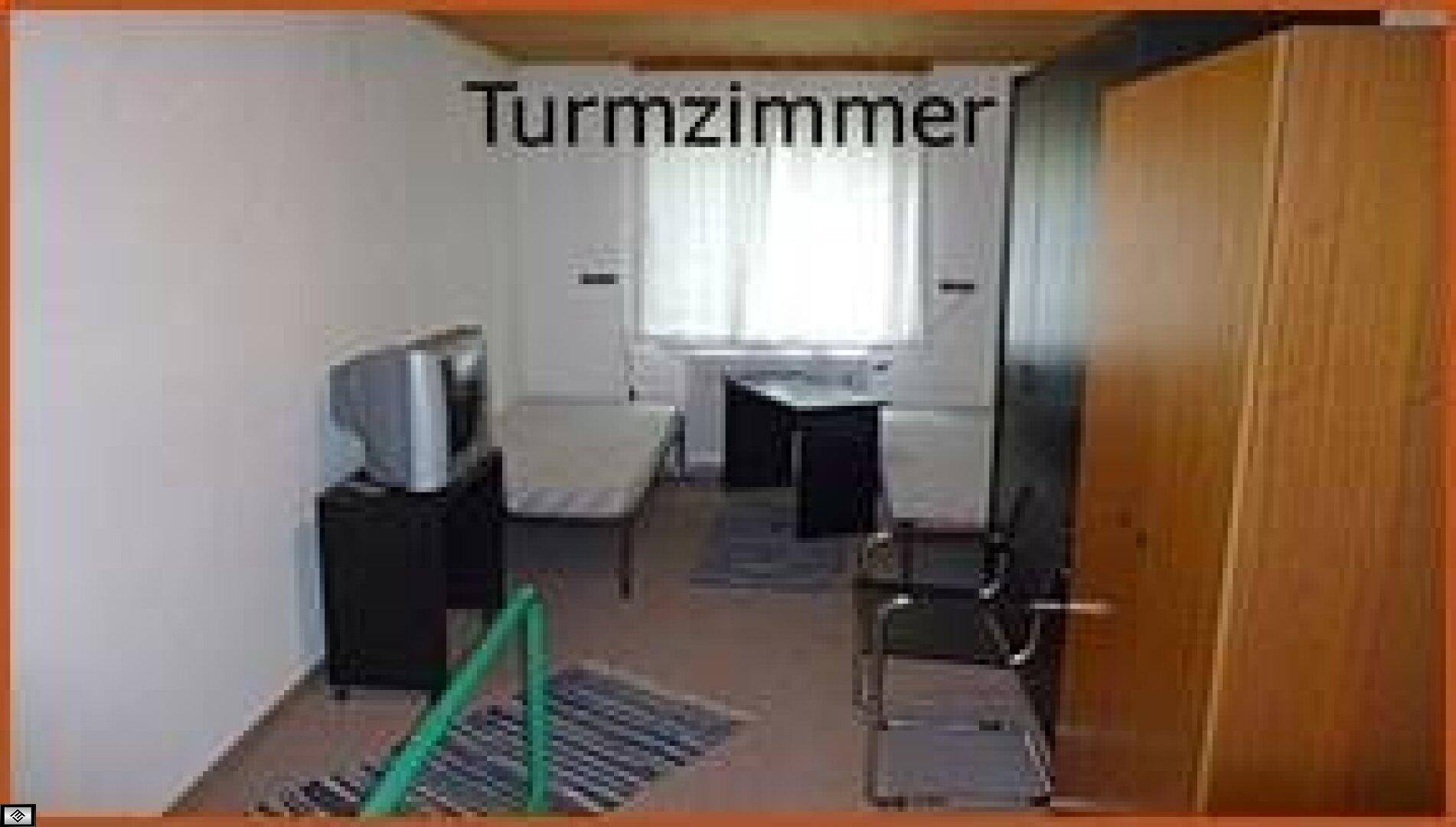 Einfach eingerichtetes Turmzimmer mit Bett, Schreibtisch, Fernseher und einem Kleiderschrank.