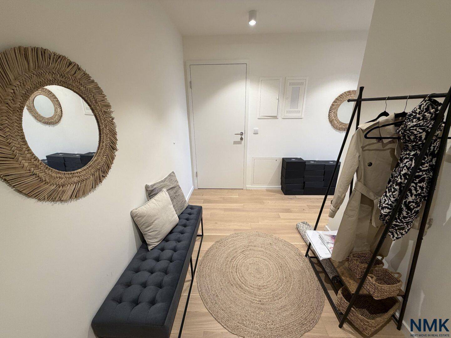 Heller Eingangsbereich mit Holzboden, Sitzbank und dekorativen Spiegeln an der Wand.