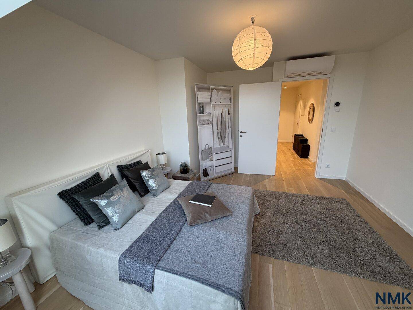 Schlafzimmer mit Holzboden, großem Bett, Kleiderschrank und Klimaanlage über der Tür.