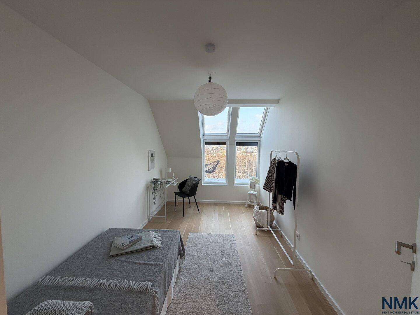 Helles Schlafzimmer im Dachgeschoss mit Holzboden, Einzelbett und schrägen Dachfenstern.