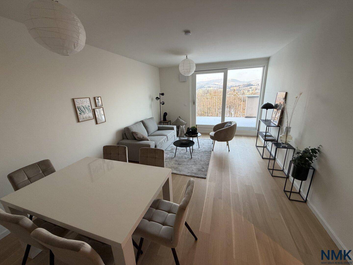 Offener Wohn-Essbereich mit Holzboden, Esstisch und Zugang zu einer Terrasse mit Weitblick.