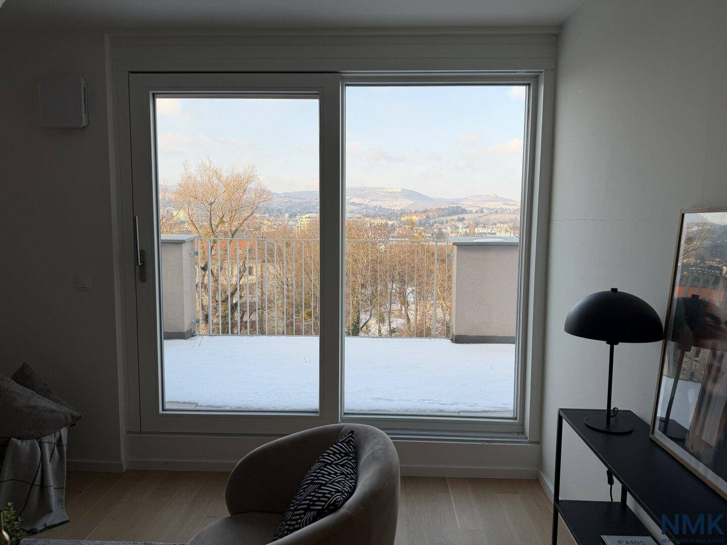 Große Schiebefenster bieten einen weiten Blick über die verschneite Landschaft und Stadt.