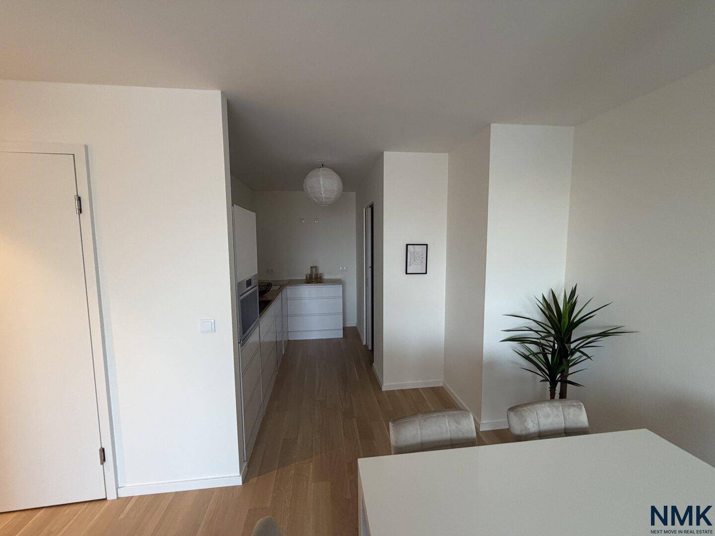 Moderne, offene Küche mit weißen Schränken und Holzboden, angrenzend an den Essbereich.