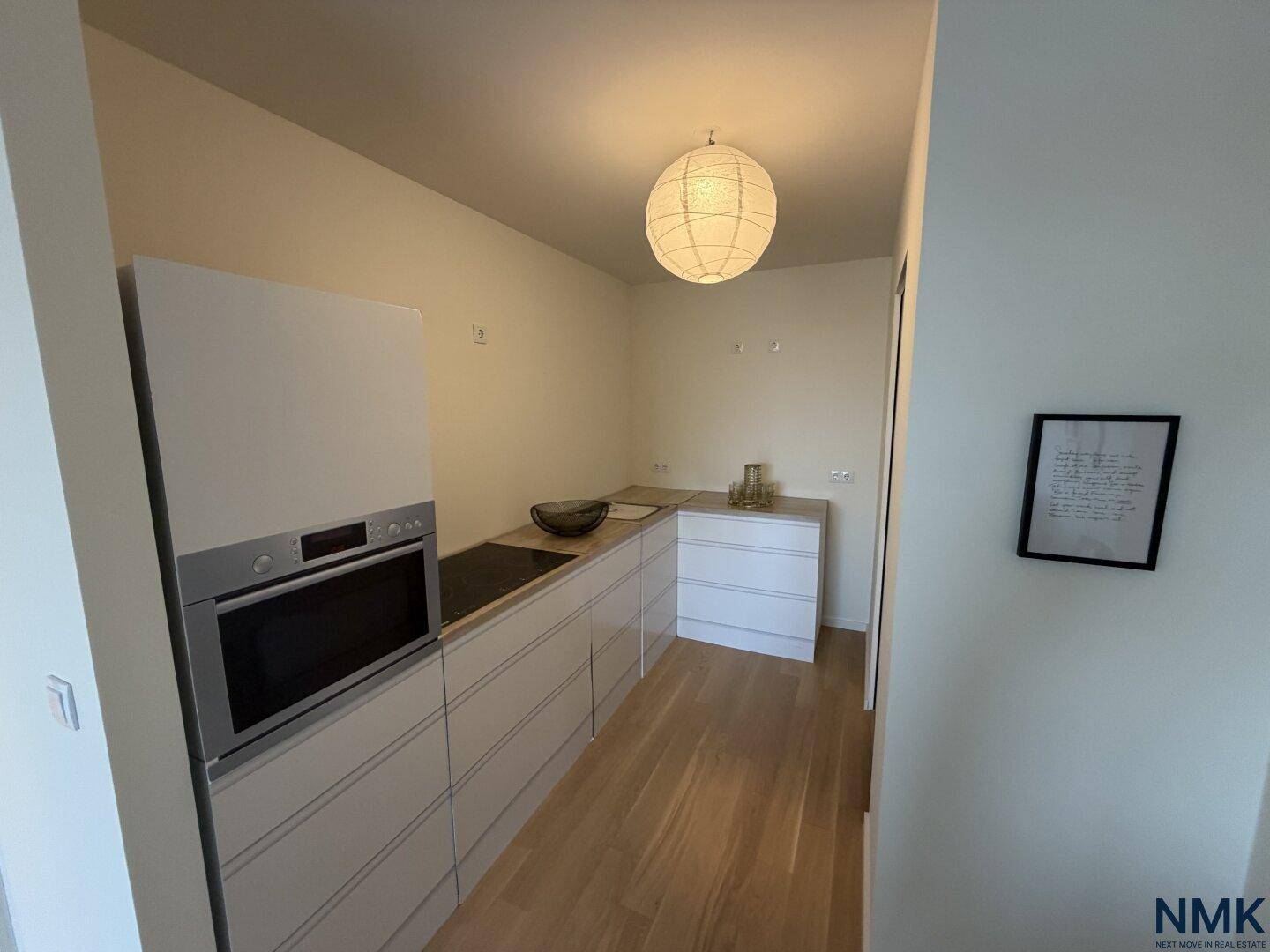 Moderne Einbauküche mit weißen Hochglanzfronten, integriertem Backofen und Kochfeld.