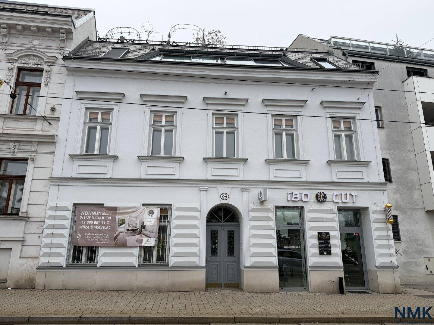 Historisches Gebäude mit moderner Fassade und Geschäftsräumen im Erdgeschoss.