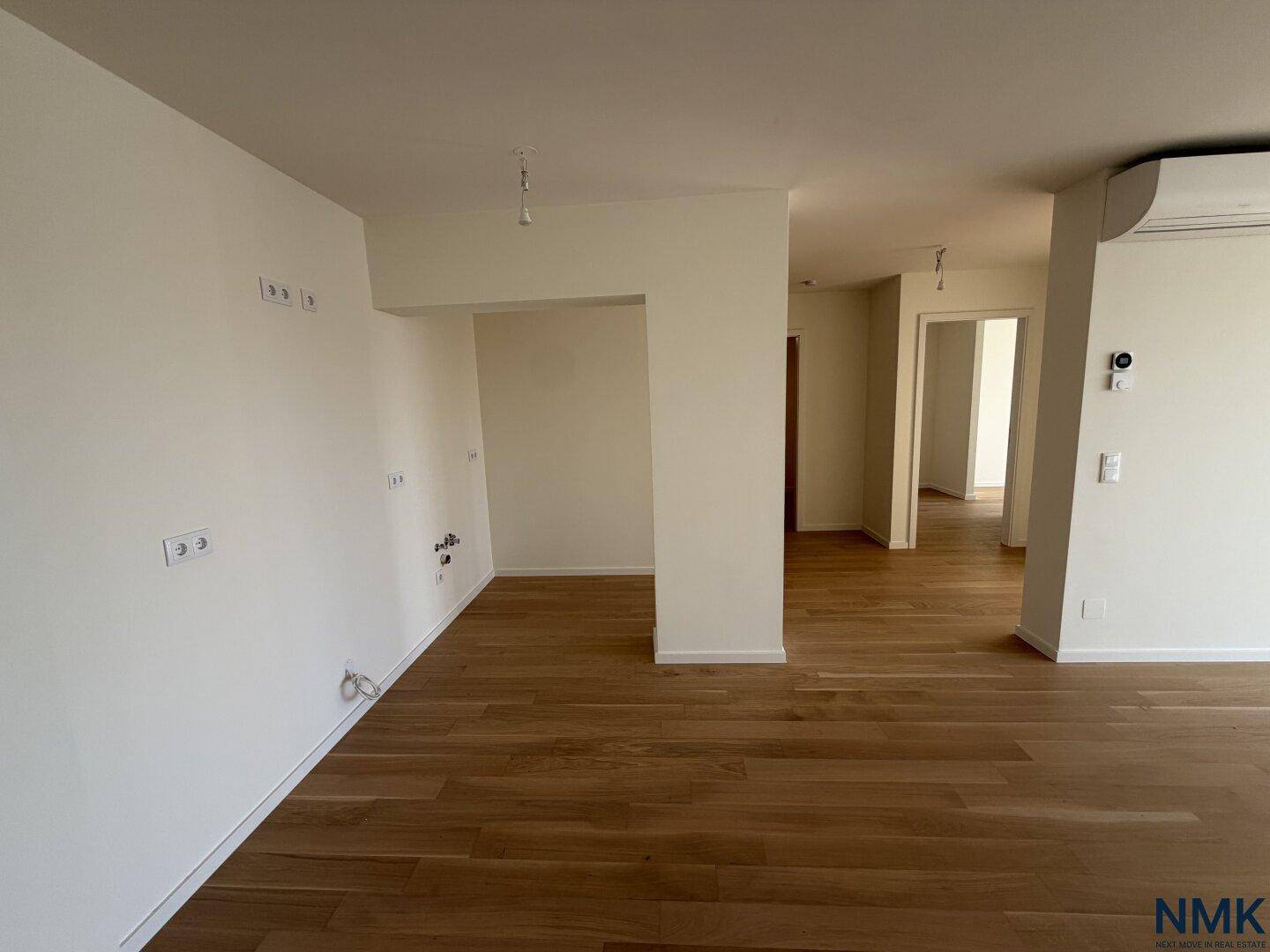 Leerer Küchenbereich mit Anschlüssen und Holzboden, bereit für die Installation einer modernen Küche.