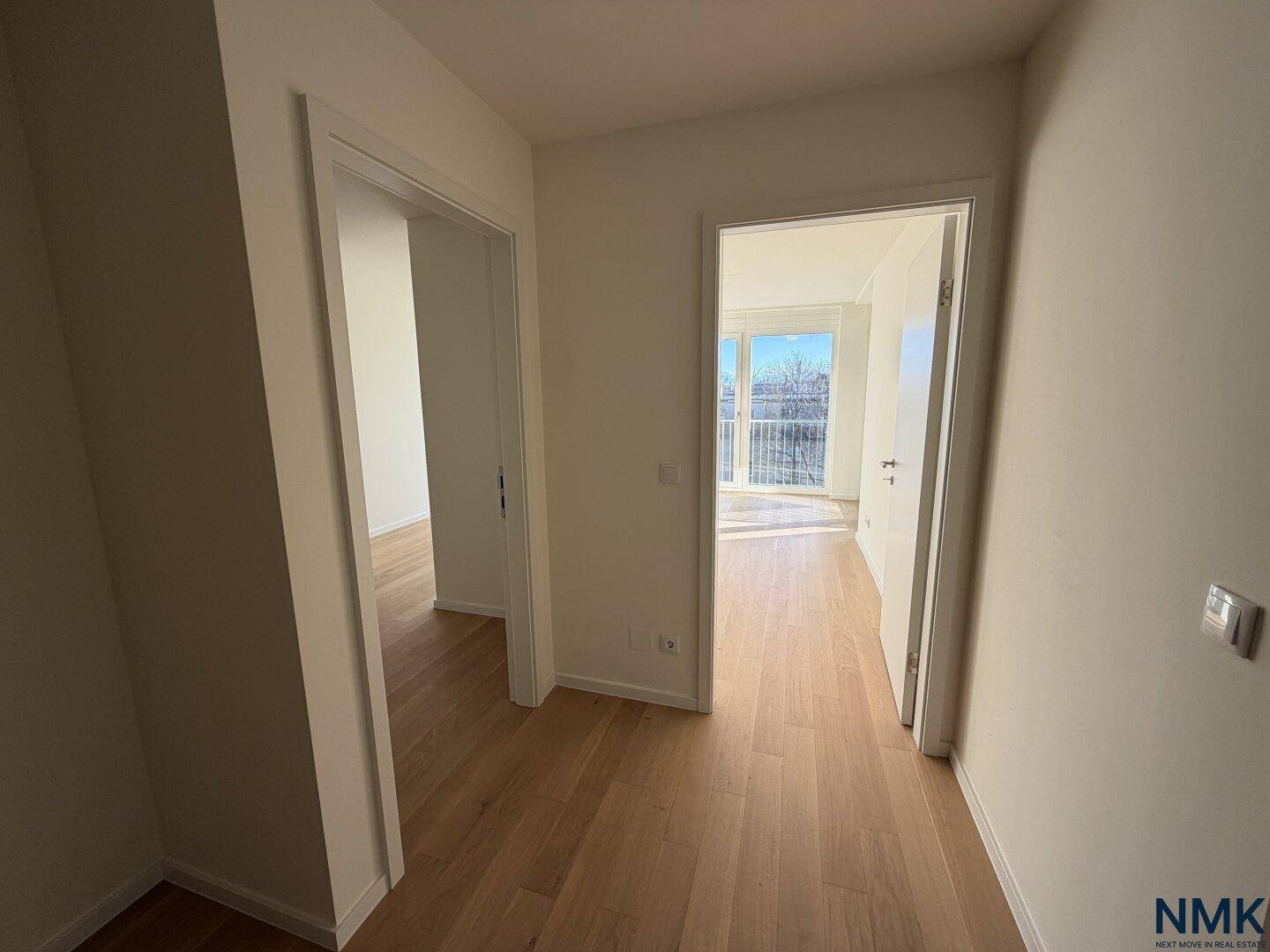 Heller Flur mit Holzboden und Zugang zu verschiedenen Räumen, der viel Tageslicht empfängt.