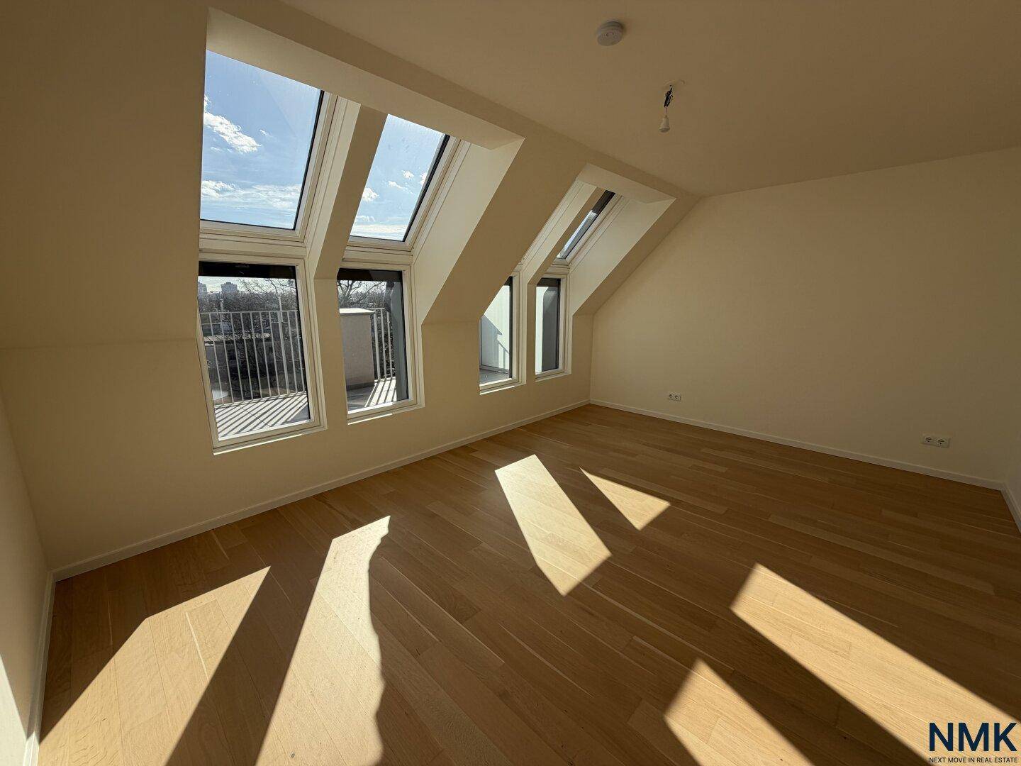 Helles Schlafzimmer mit Holzboden, Dachschrägen und großen Dachfenstern mit Blick.