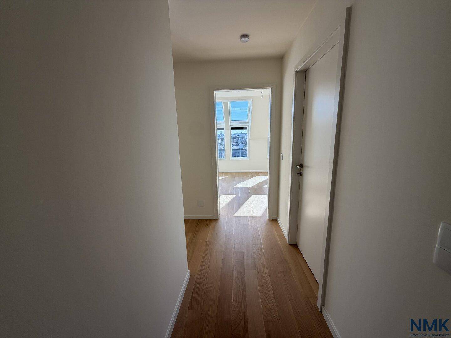 Heller Flur mit Holzboden und weißen Türen, der zu weiteren Räumen führt.