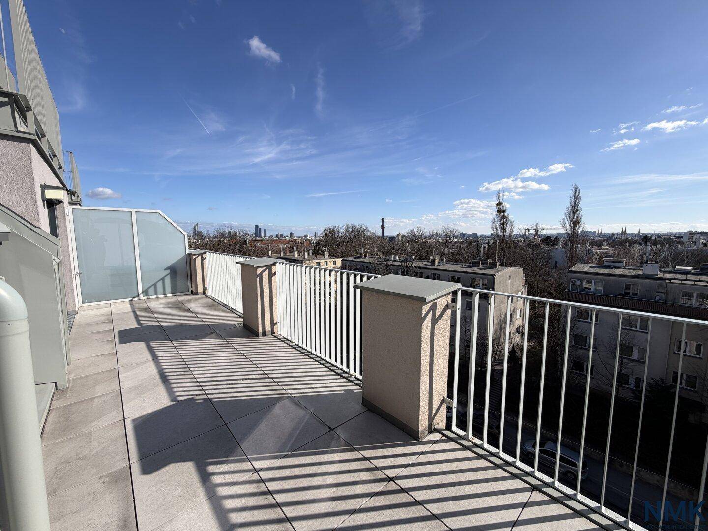 Weitläufige Dachterrasse mit Fliesenboden und Panoramablick über die Stadt.