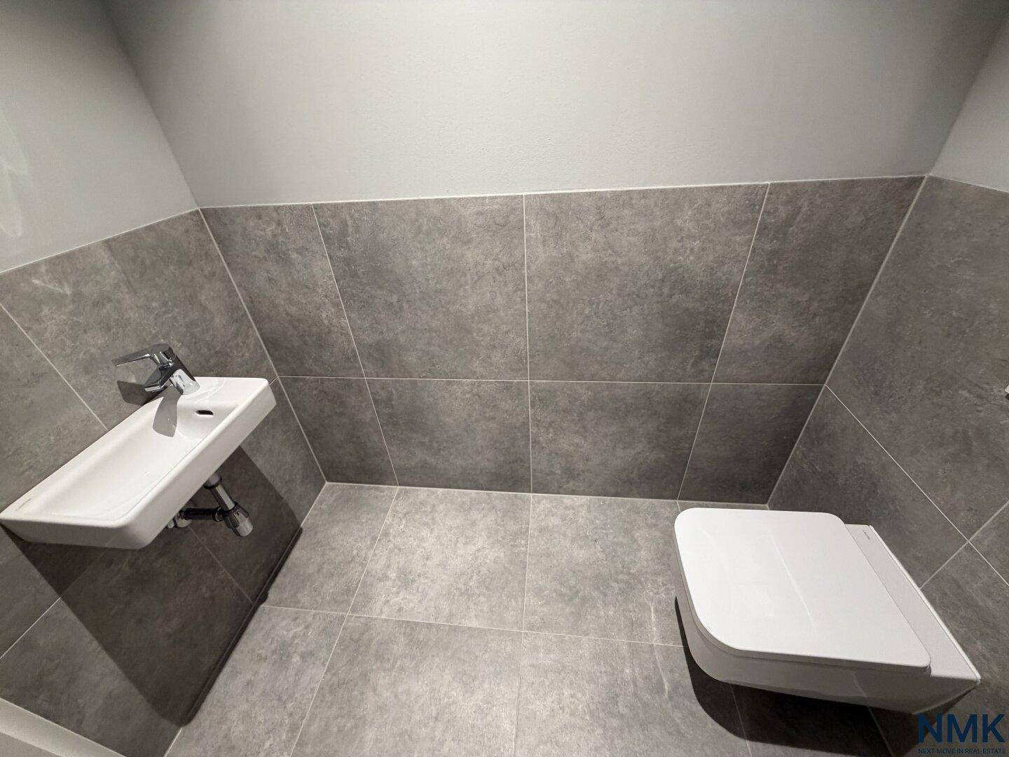 Modernes Gäste-WC mit Wand-WC und kleinem Waschbecken, komplett gefliest.