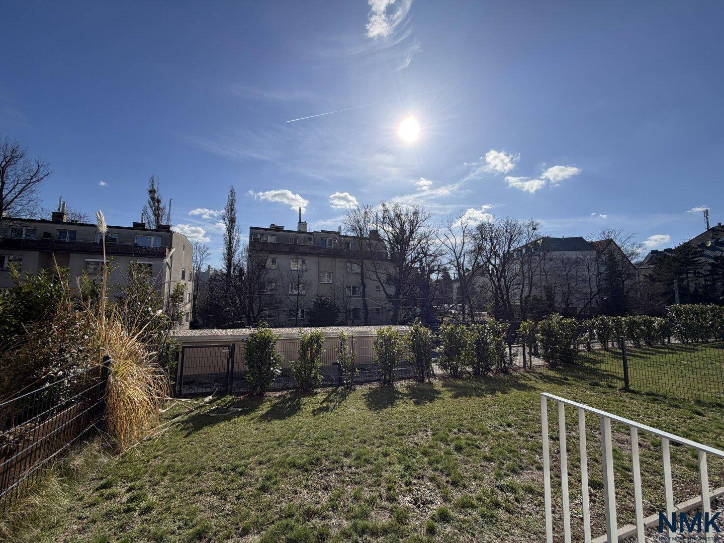 Sonniger Gemeinschaftsgarten mit Rasenfläche und Blick auf die umliegenden Wohngebäude.