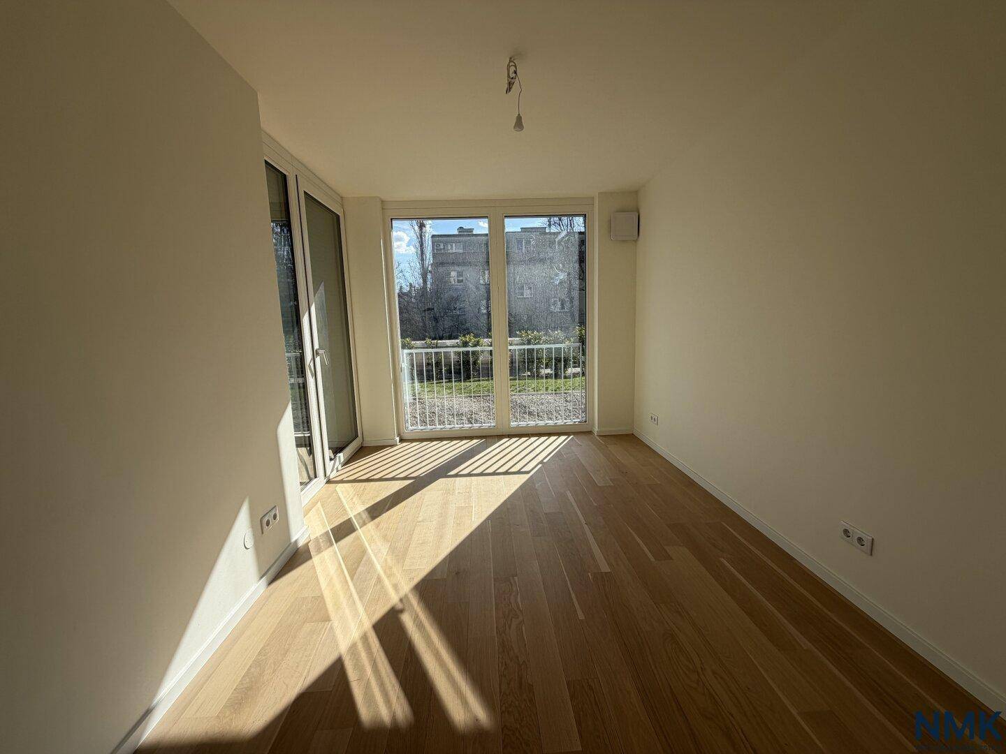 Helles Schlafzimmer mit Holzboden und französischem Balkon, bietet viel Tageslicht.