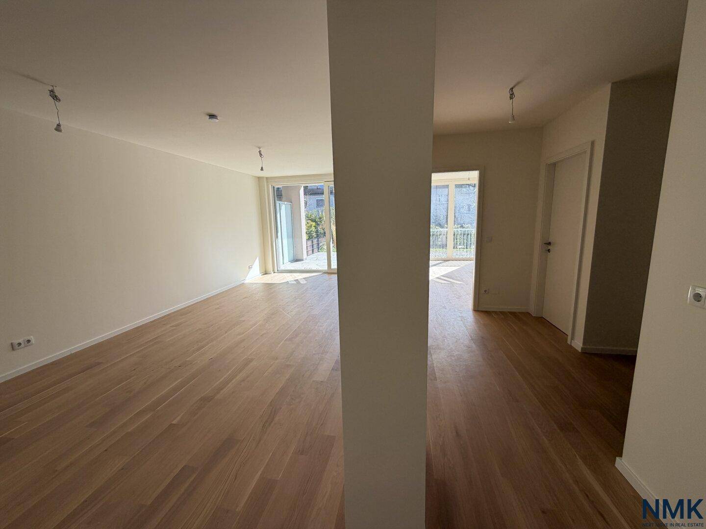 Heller, offener Wohn- und Essbereich mit Holzboden und Zugang zu einer Außenterrasse.