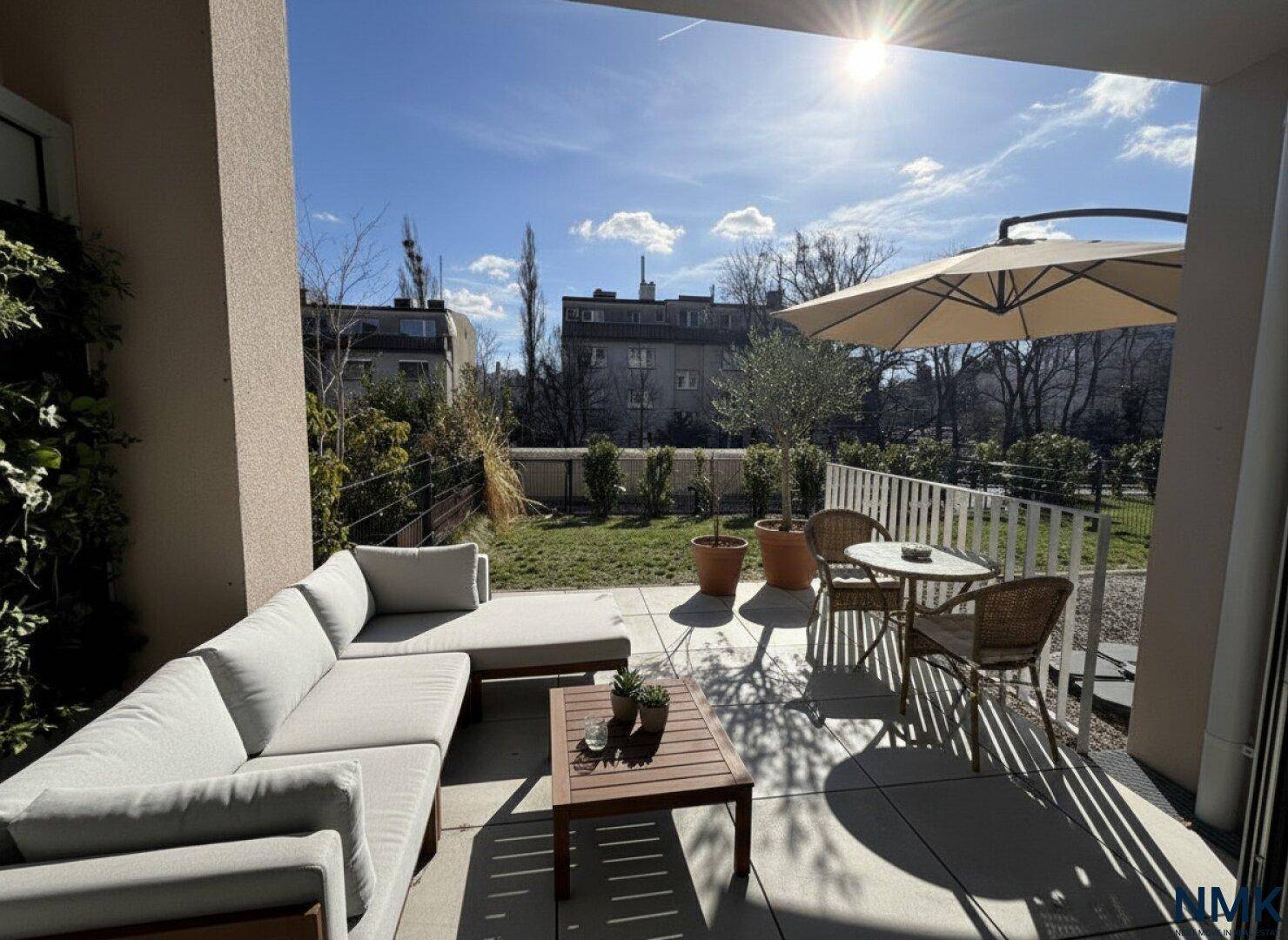 Möblierte Sonnenterrasse mit Lounge-Sofa, Esstisch und Blick auf den Gartenbereich.