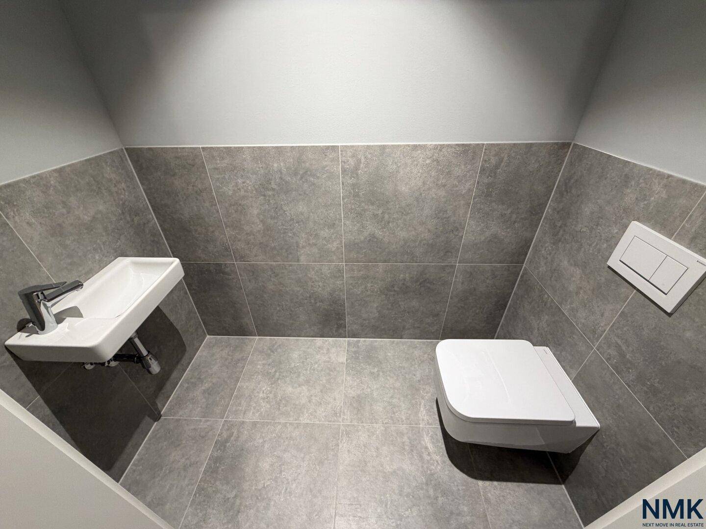 Sauber und funktional gestaltetes Gäste-WC mit Fliesen und Wand-WC.
