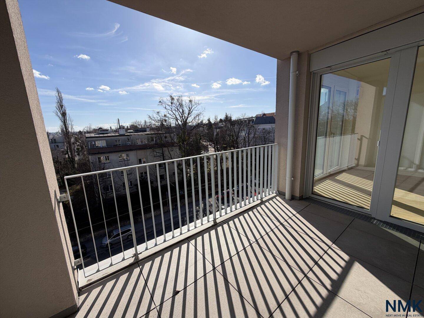 Heller Balkon mit Fliesenboden und weitem Blick über die städtische Umgebung.
