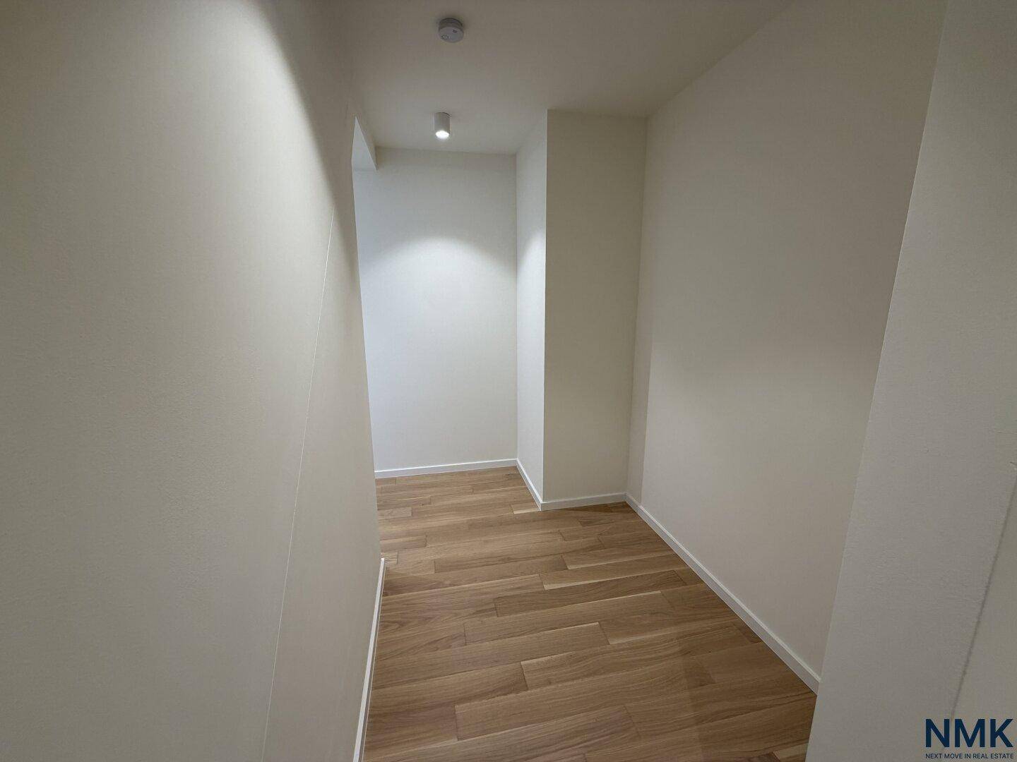 Heller, leerer Flur mit Holzboden und schlichten weißen Wänden, bereit zur individuellen Gestaltung.
