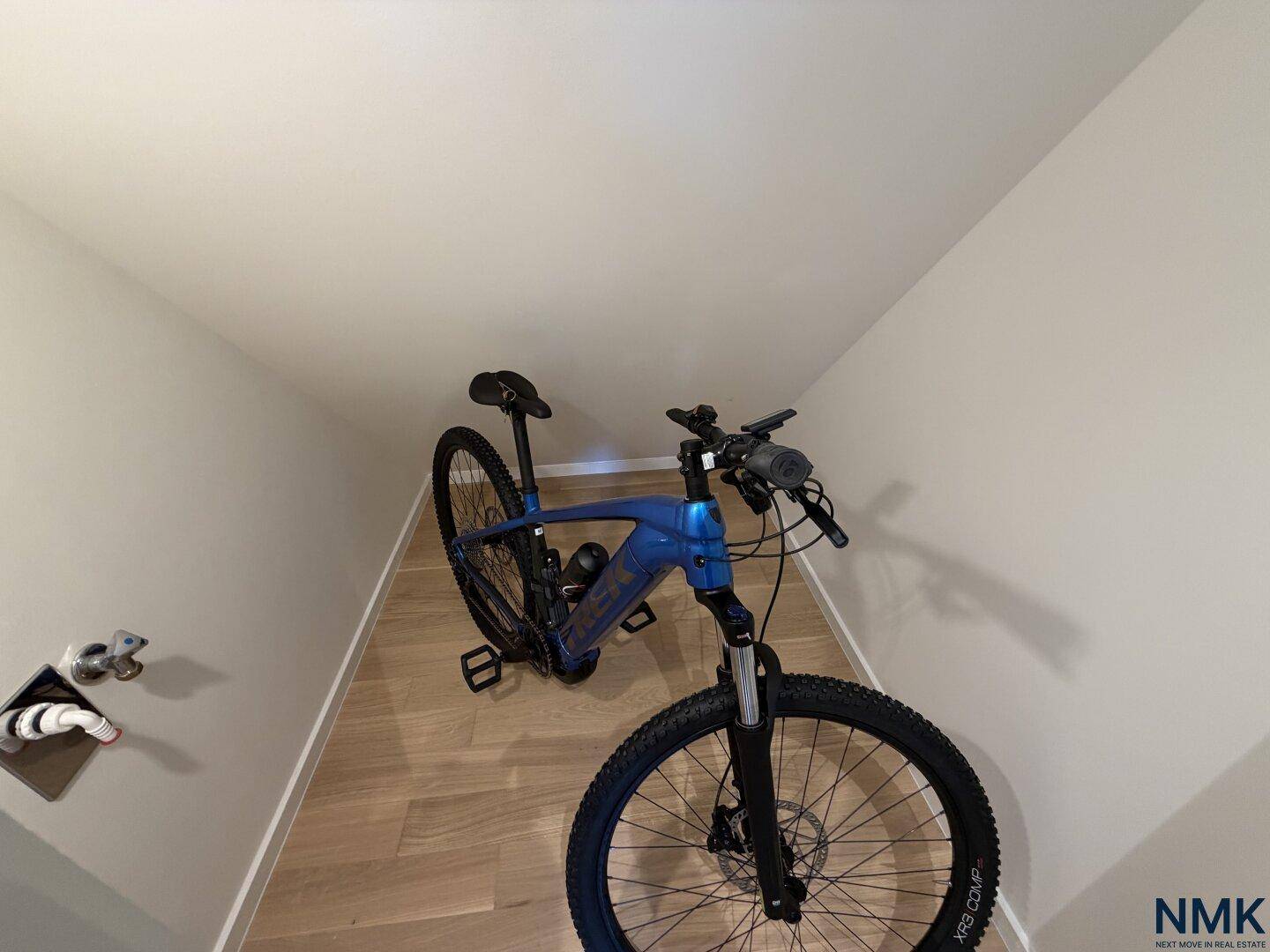Praktischer Abstellraum mit Fahrrad und Wasseranschlüssen unter einer Dachschräge.