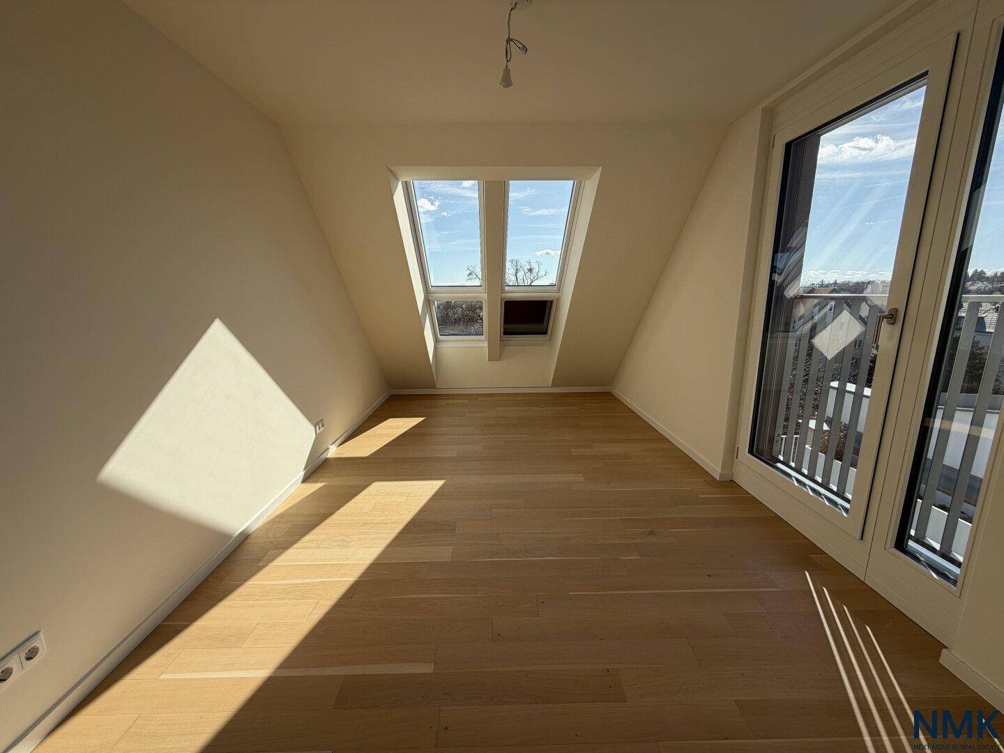 Heller, leerer Raum mit Holzboden, großen Fenstern und Dachschrägen, ideal als Schlafzimmer.