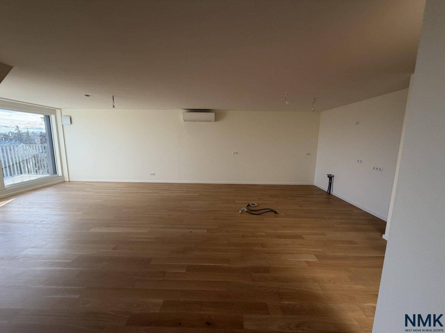Großer, heller Raum mit Holzboden, großen Fenstern und Klimaanlage.