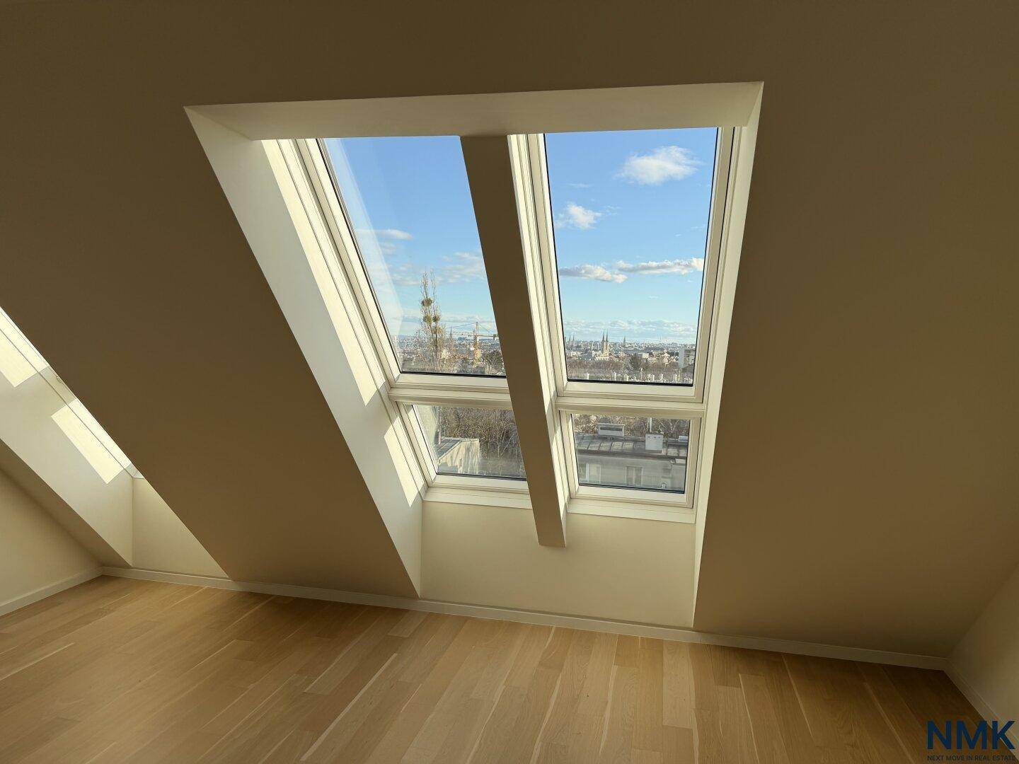 Nahaufnahme der Dachfenster mit klarem Blick auf die Stadt und den blauen Himmel.