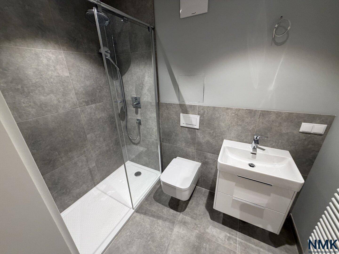 Modernes Badezimmer mit ebenerdiger Dusche, WC und Einzelwaschbecken.