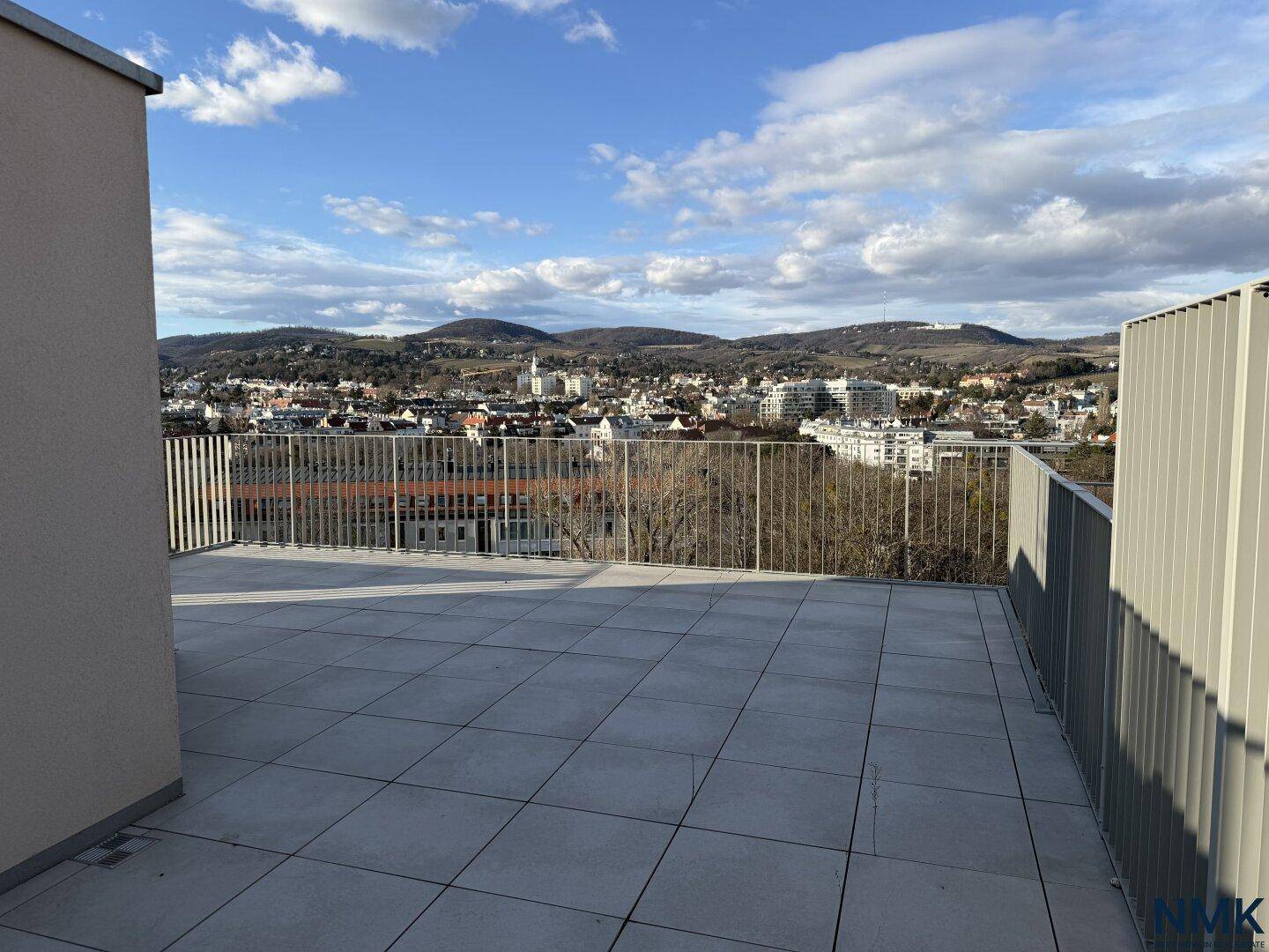 Geräumige Dachterrasse mit Fliesenboden und weitem Blick auf Hügel und die umliegende Landschaft.