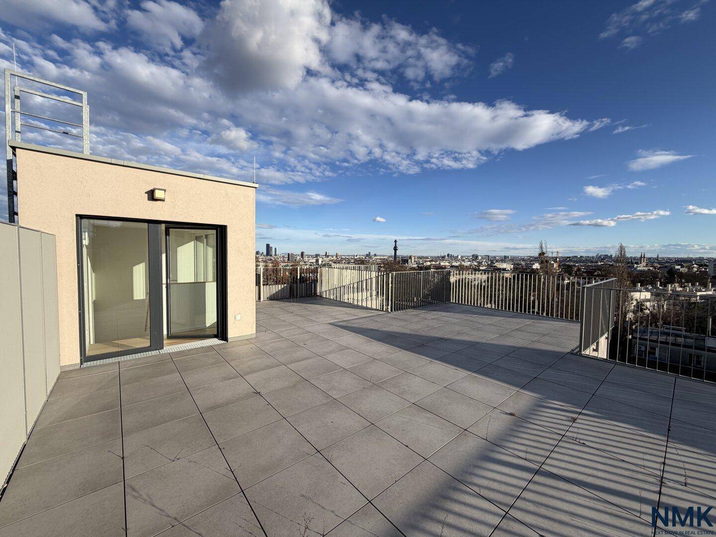 Große, leere Dachterrasse mit Fliesenboden und weitem Panoramablick über die Stadt.