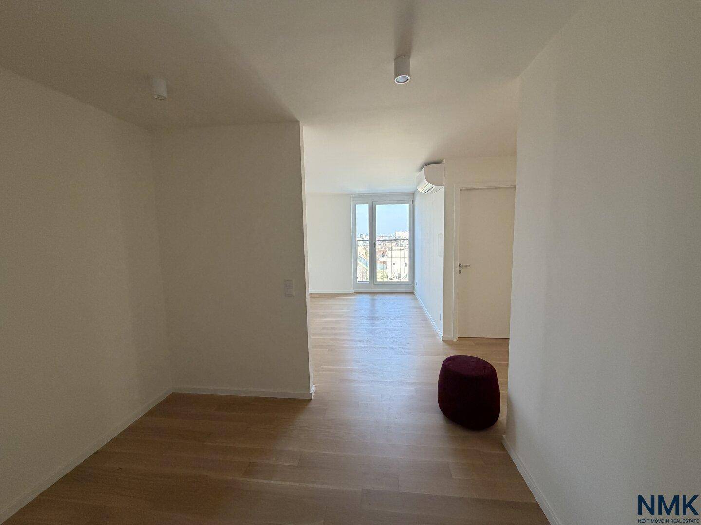 Heller Flur mit Holzboden und Blick auf einen weiteren Raum mit Balkonzugang.
