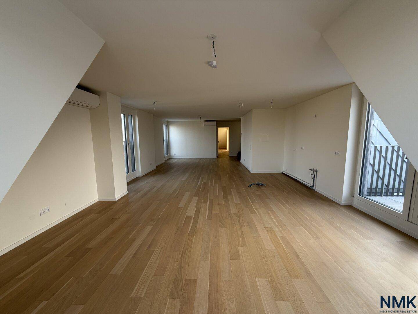 Heller, leerer Wohn-Essbereich mit Holzboden und großen Fenstern, bereit zur Einrichtung.
