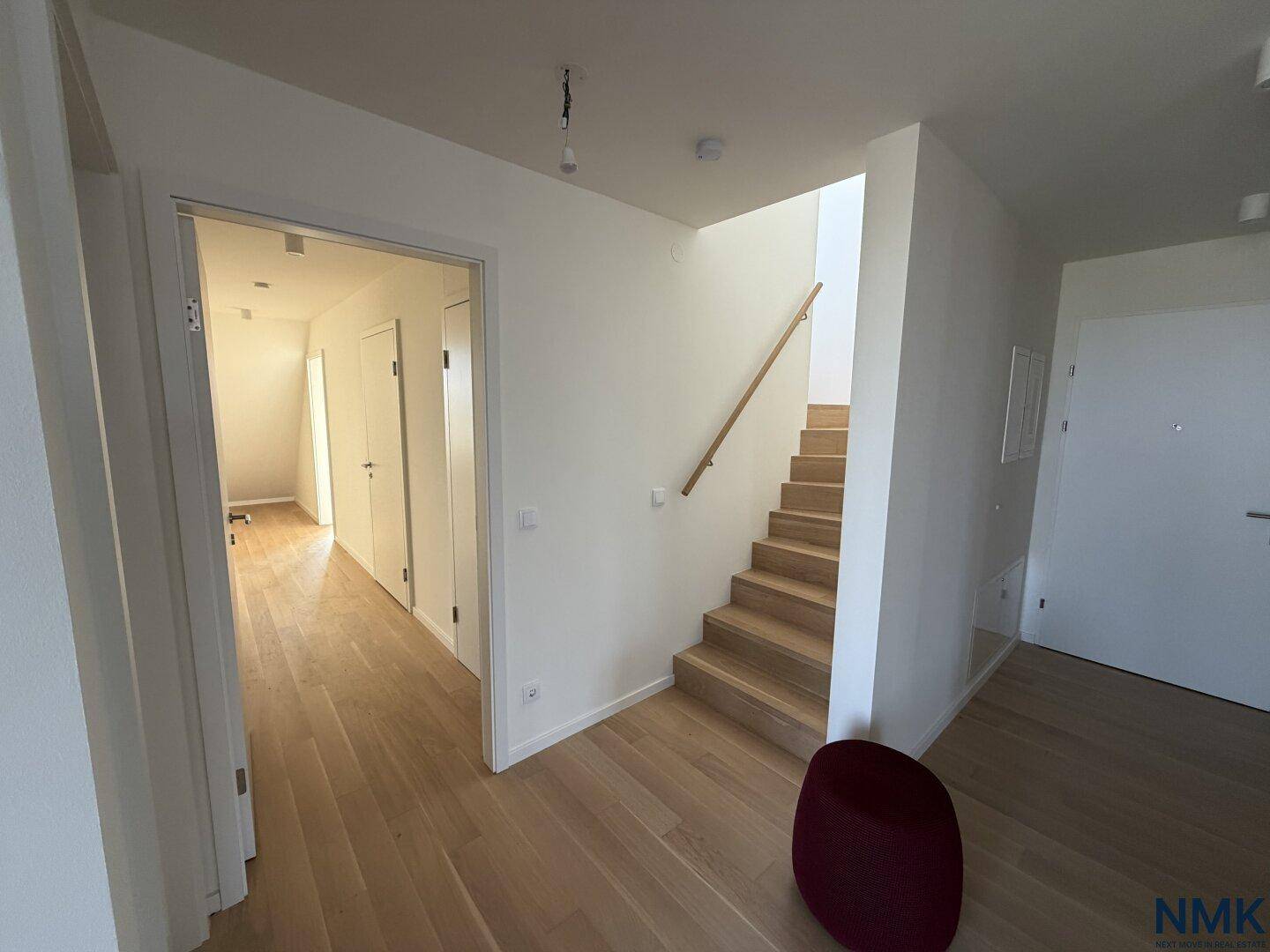 Heller Flur mit Holztreppe und Zugang zu weiteren Räumen, modern gestaltet.
